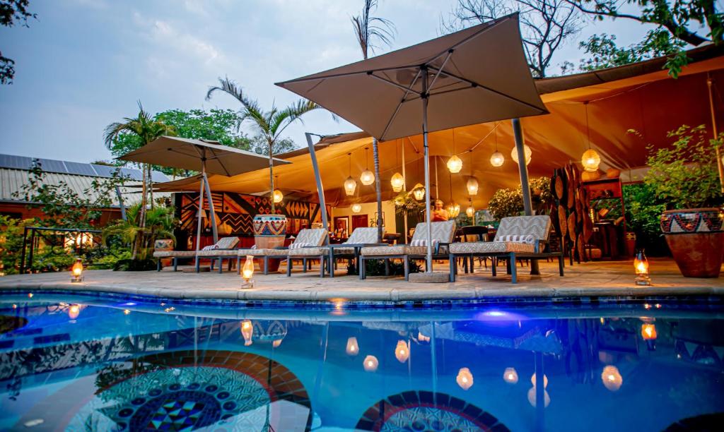 - une piscine avec des tables, des chaises et des parasols dans l'établissement Shongwe Lookout, à Victoria Falls