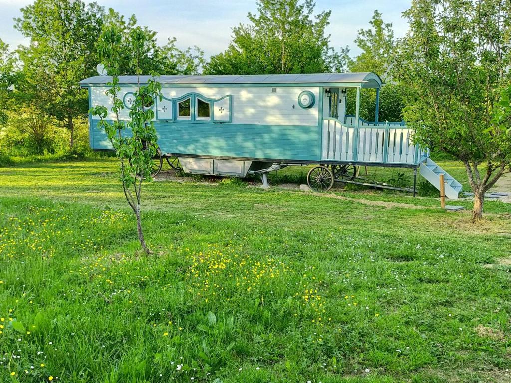 a blue train car sitting in a field of grass at Gîtes Les Perouilles - La Roulotte Climatisée avec Jacuzzi de Josépha in Puymiclan