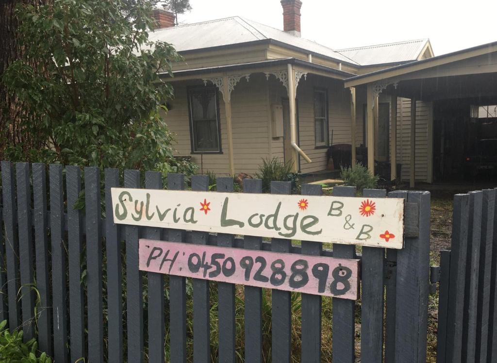 un panneau sur une clôture devant une maison dans l'établissement Sylvia Lodge A step back in time pet friendly Homestay, à Orbost