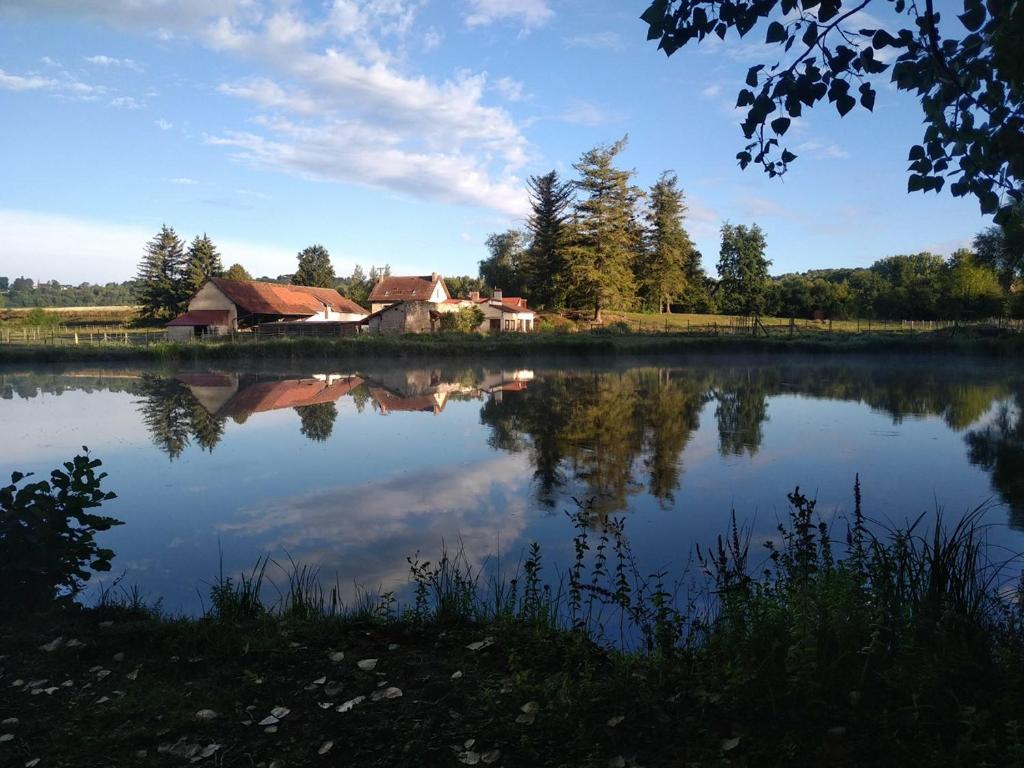 un reflejo de una casa en un lago en Le moulin Bertrand, en Martigny-Courpierre