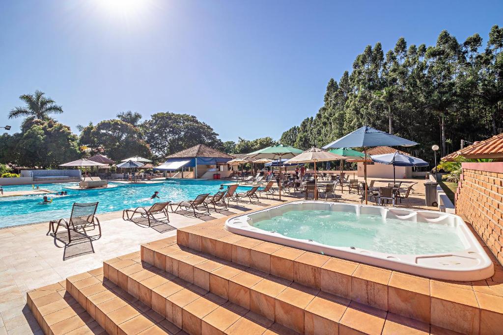 uma grande piscina com cadeiras e guarda-sóis num resort em Santa Eliza Eco Resort em Ribeirão Bonito