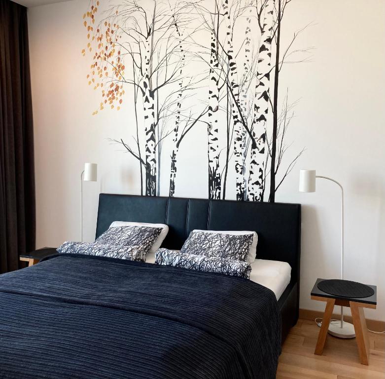 sypialnia z łóżkiem i drzewami na ścianie w obiekcie Baltiq Plaza Apartment w mieście Gdynia