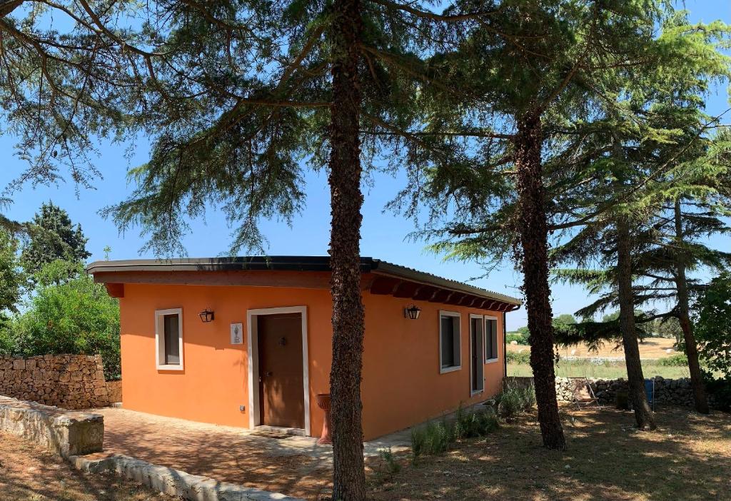une petite maison orange au milieu des arbres dans l'établissement Barsentello, à Noci