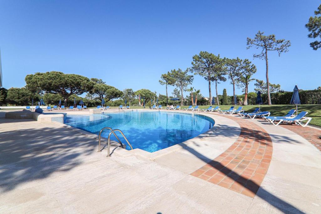 une grande piscine avec des chaises et des arbres dans l'établissement Apartment Dansk, à Almancil