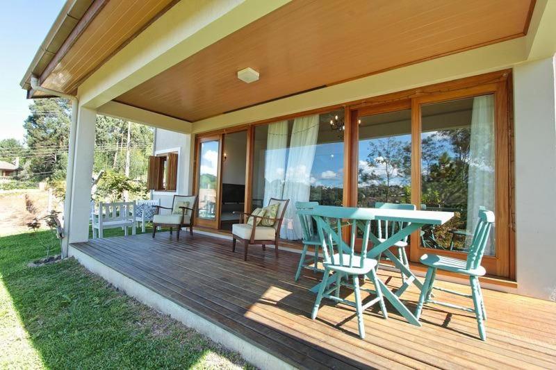 una terraza con mesa y sillas en una casa en Familiar da Colina - My Home Temporada, en Gramado