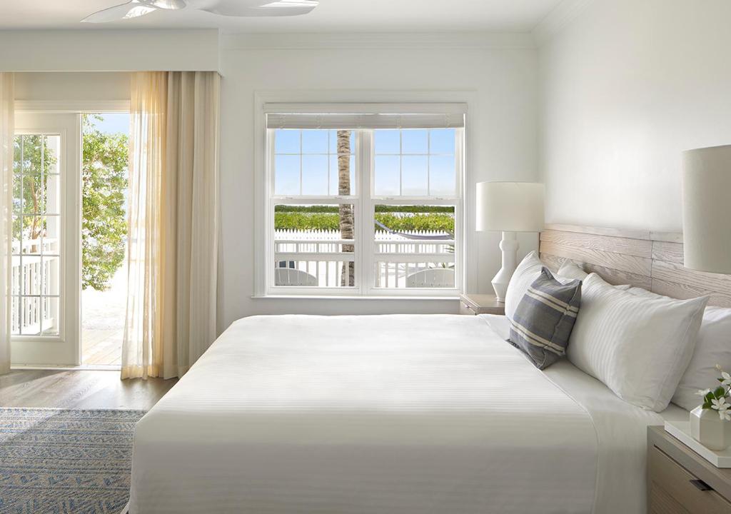 ein weißes Schlafzimmer mit einem großen Bett und einem Fenster in der Unterkunft Parrot Key Hotel &amp; Villas in Key West