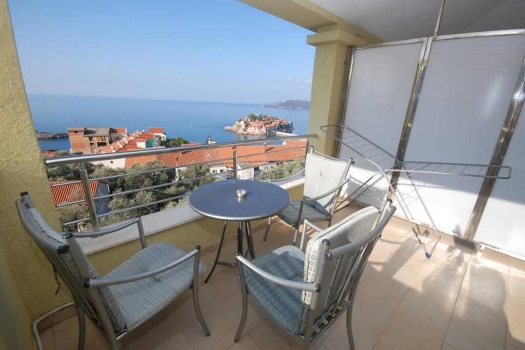 a balcony with a table and chairs and a view of the ocean at BMV room with east island view in Sveti Stefan