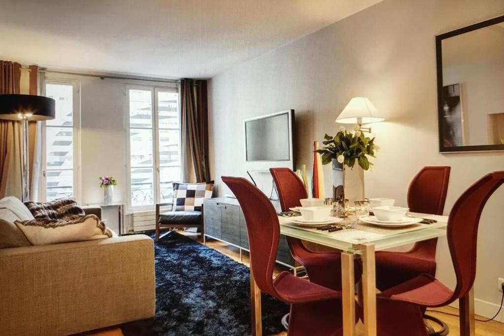 a living room with a table and chairs and a couch at Appartement Champs-Elysées Montaigne - HALA PARIS in Paris