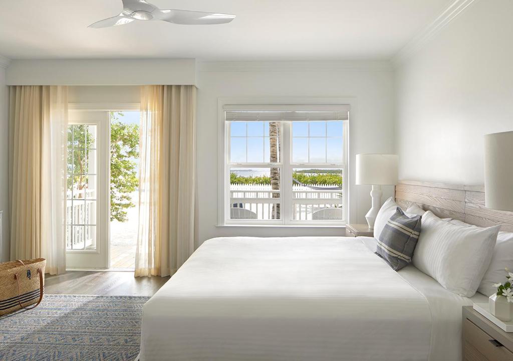 ein weißes Schlafzimmer mit einem großen Bett und einem Fenster in der Unterkunft Parrot Key Hotel &amp; Villas in Key West