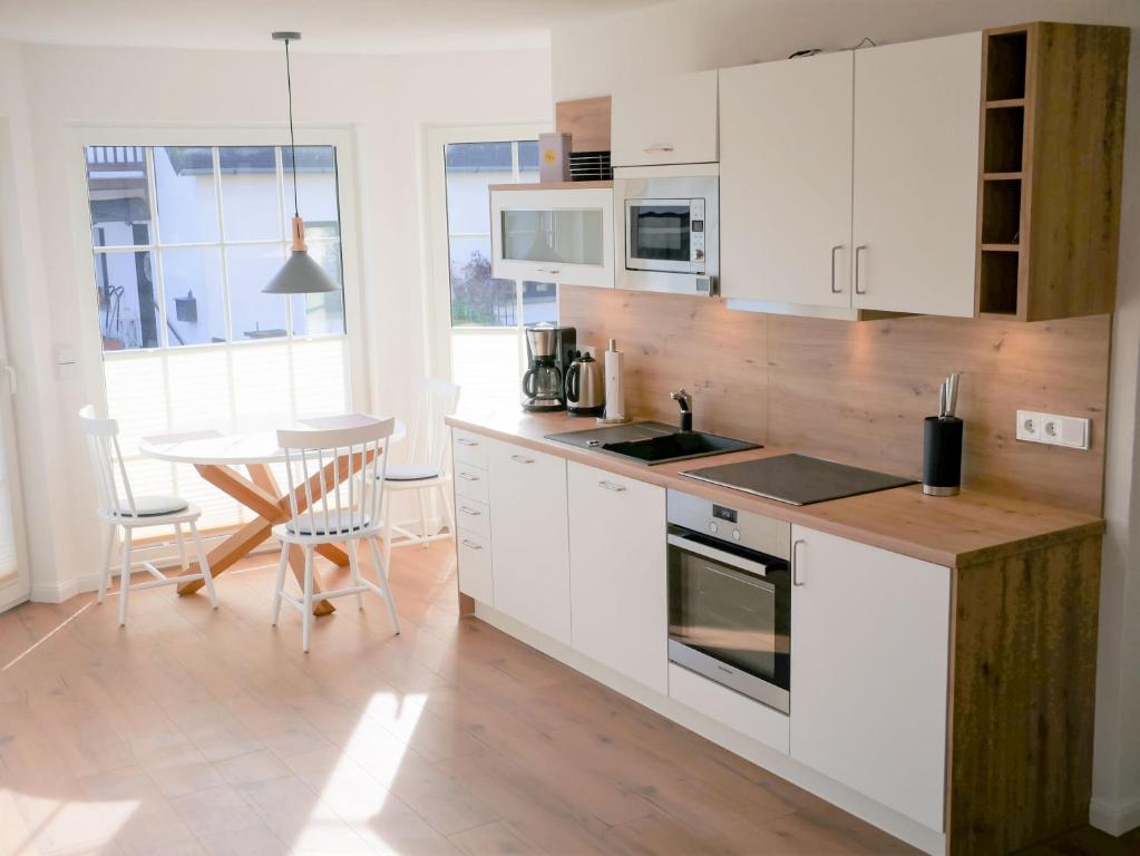 a kitchen with white cabinets and a table at Reethaus Boddenblick - Apt. 09 in Alt Reddevitz