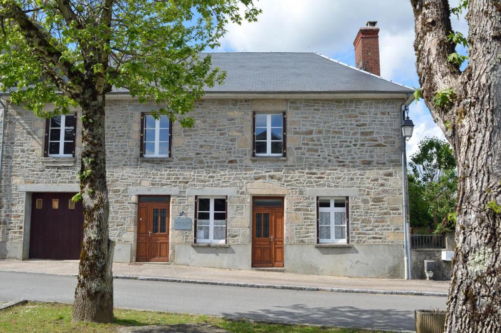 una casa de ladrillo con puertas marrones y un árbol en Champ De Foire en Sussac