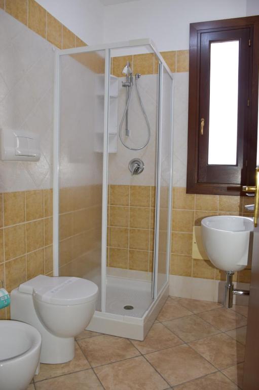 a bathroom with a shower and a toilet and a sink at Hotel Sikania in San Vito lo Capo