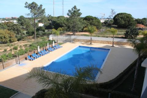 a large swimming pool with blue chairs and trees at Quinta do Pinheiro Premium by Sunny Deluxe in Olhos de Água