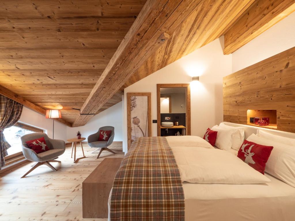 sypialnia z dużym łóżkiem i drewnianym sufitem w obiekcie FIORI Dolomites Experience Hotel w mieście San Vito di Cadore