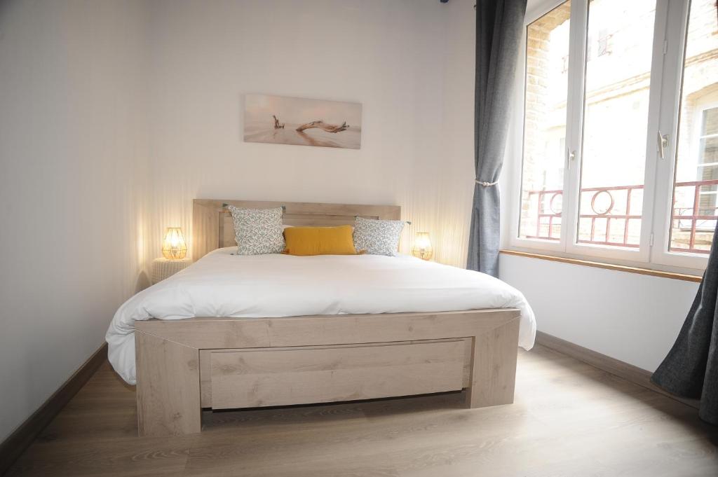 Schlafzimmer mit einem Bett mit weißer Bettwäsche und gelben Kissen in der Unterkunft Au colombage bleu 2 à 4 pers in Dieppe