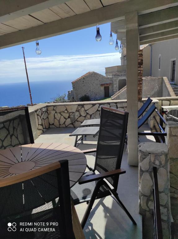 una mesa y sillas en un patio con vistas al océano en Lubenice-Rodinis Room and Apartment en Lubenice