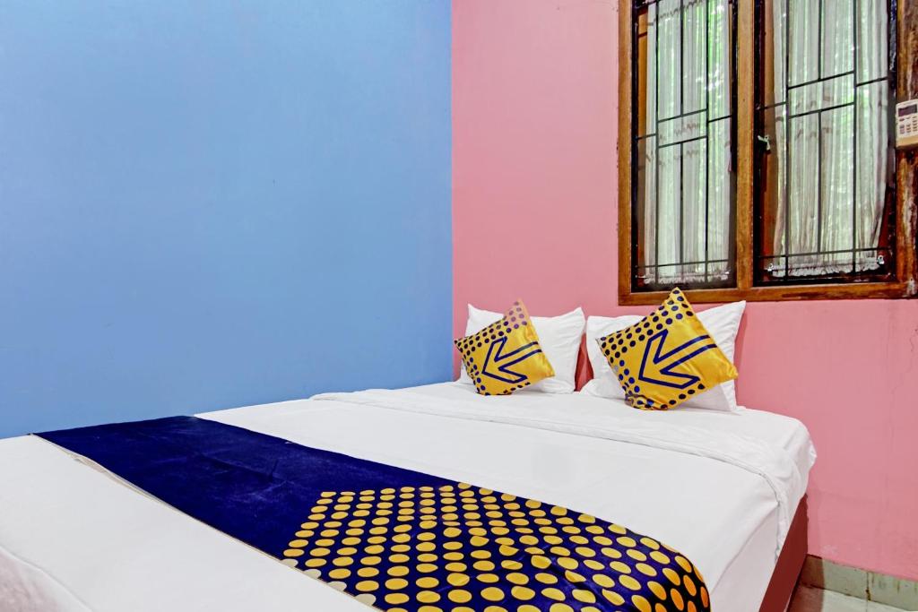 Bett in einem Zimmer mit farbenfrohen Wänden und Fenstern in der Unterkunft OYO 90268 Aliyah Syariah in Jakarta