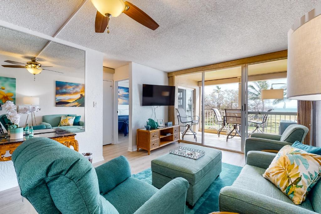 a living room with a couch and chairs and a tv at Menehune Shores in Kihei