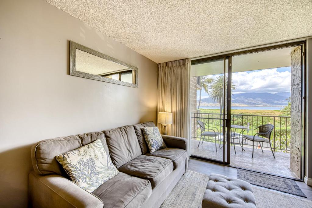 a living room with a couch and a balcony at Kauhale Makai in Kihei