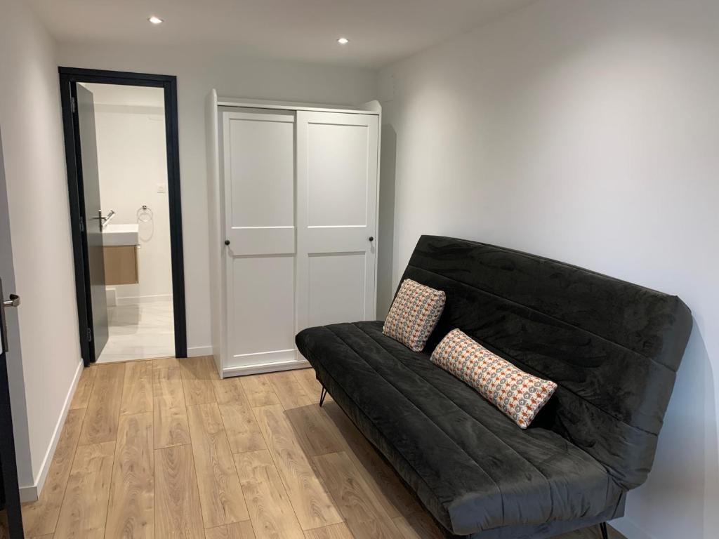 a black couch in a living room with a mirror at Nanterre Room in Nanterre