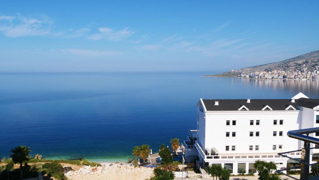 a white building on the shore of a body of water at Beva Hotel in Sarandë