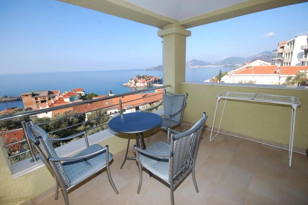a balcony with a table and chairs and a view of the ocean at BMV room with west island view in Sveti Stefan