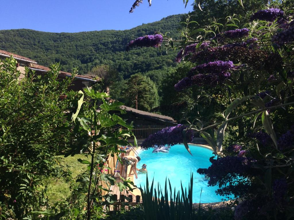 una piscina en un jardín con flores púrpuras en Gîte Tanagra : Maison avec piscine et vue exceptionnelle en Roquefort-les-Cascades