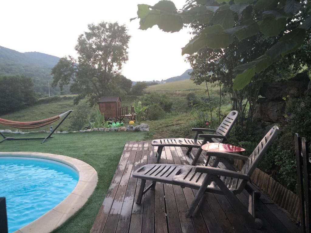 a deck with two chairs next to a swimming pool at Gîte Tanagra : Maison avec piscine et vue exceptionnelle in Roquefort-les-Cascades