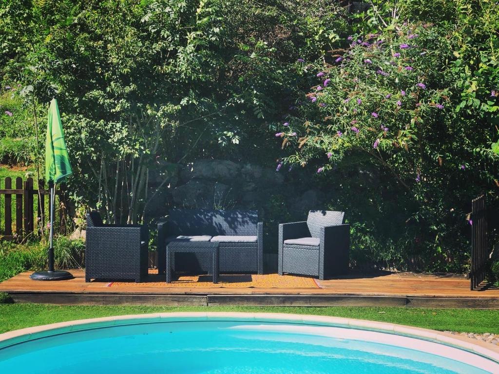 two chairs sitting next to a swimming pool at Gîte Tanagra : Maison avec piscine et vue exceptionnelle in Roquefort-les-Cascades