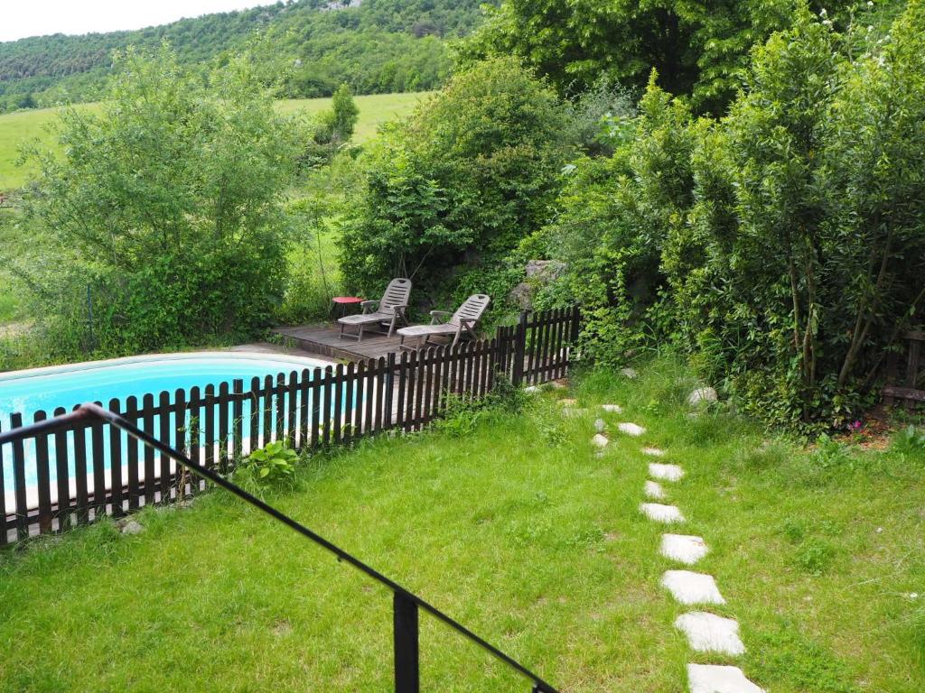 a fence with two chairs and a pool in a yard at Gîte Tanagra : Maison avec piscine et vue exceptionnelle in Roquefort-les-Cascades