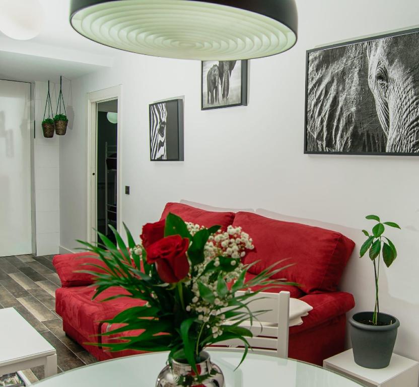 een woonkamer met een rode bank en een tafel met bloemen bij El Rincón de Eva in Salamanca