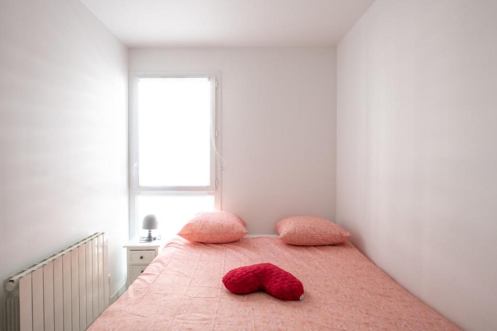 a bedroom with a bed with two red pillows on it at Le Casper - Charmant appartement au calme proche centre-ville in Lyon