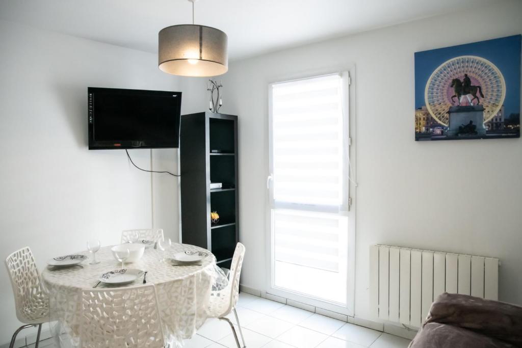 a white dining room with a table and a tv at Le Casper - Charmant appartement au calme proche centre-ville in Lyon