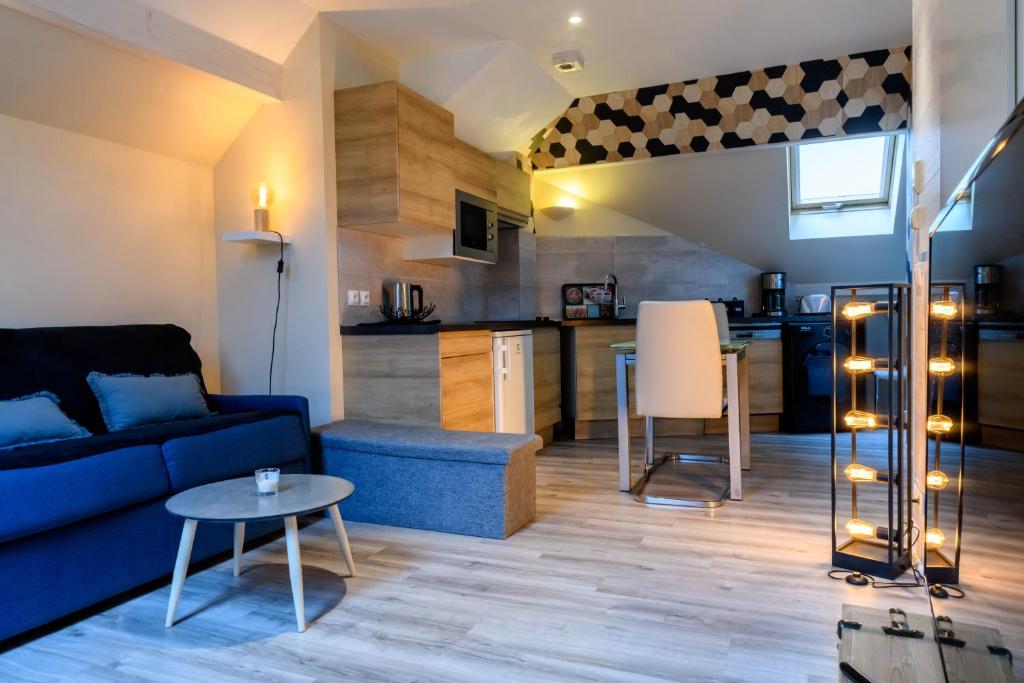 a living room with a blue couch and a kitchen at Au bord du lac d’Annecy, logement type Loft, dans résidence avec plage et ponton privée in Duingt