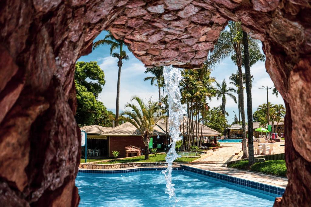 a fountain in a pool with palm trees at Caldas Park & Hotel XPTO Turismo in Caldas Novas