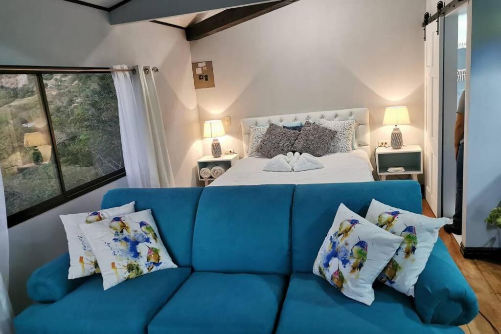 a blue couch in front of a bed with pillows at El Granero de la negra in Monteverde Costa Rica
