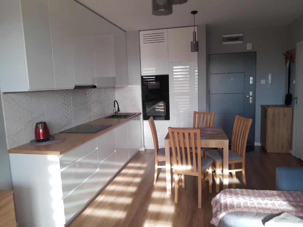 a kitchen with white cabinets and a table and chairs at Apartament na Strzeleckiej in Płock