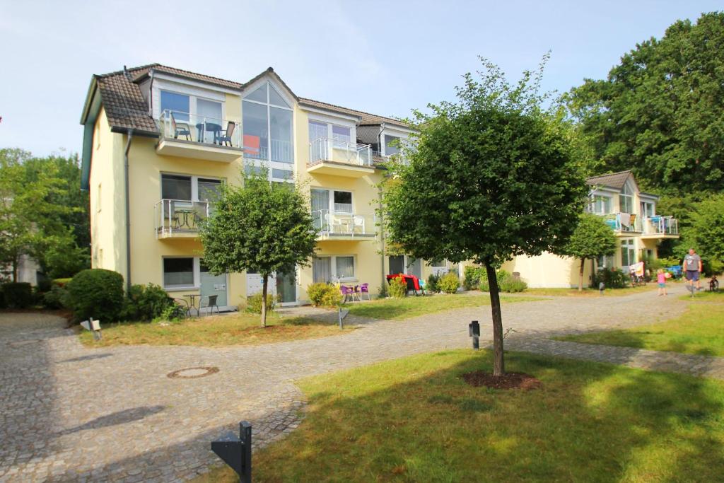 un gran edificio de apartamentos con un árbol delante en nur 100 m bis zum Strand Appartmentanlage Eldena FeWo 15 en Lobbe