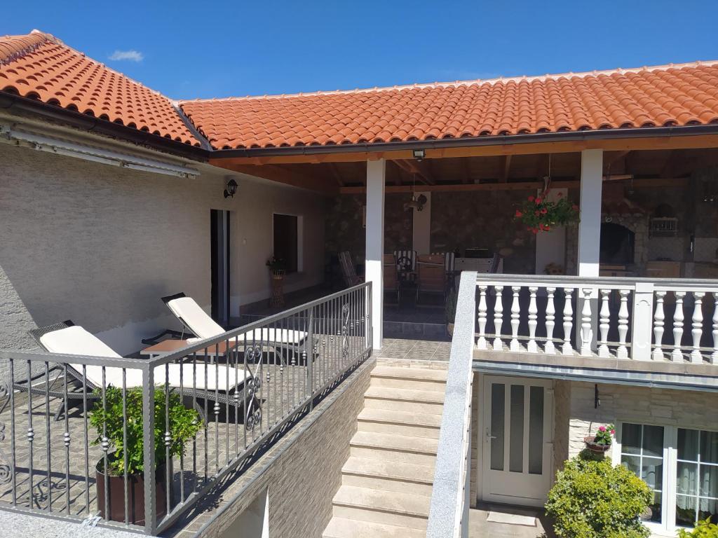 a house with a balcony with tables and chairs at Tomić in Novi Vinodolski