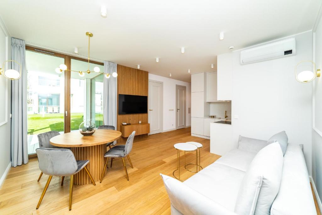 White Deluxe with terrace by OneApartments في غدانسك: غرفة معيشة مع أريكة بيضاء وطاولة