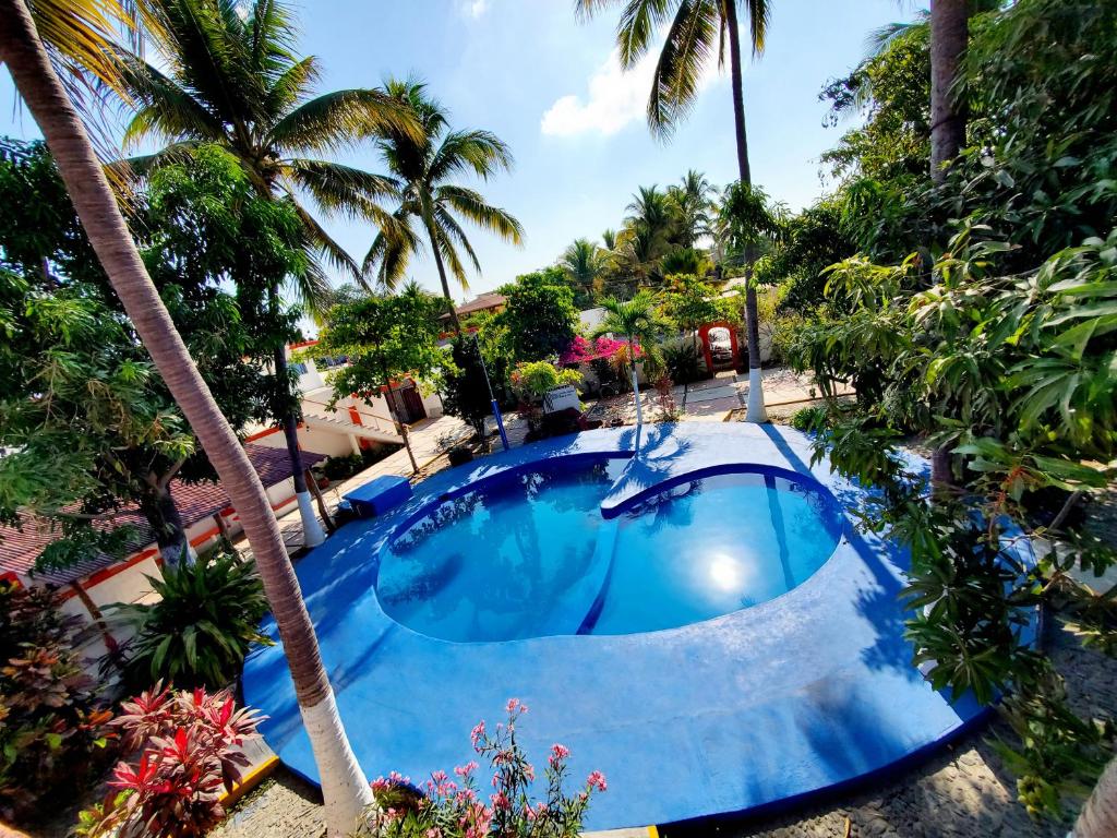 a swimming pool with palm trees and a resort at Hotel Oasis Melaque in San Patricio Melaque