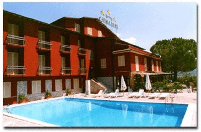 ein Hotel mit einem Pool vor einem Gebäude in der Unterkunft Hotel Cavalieri in Passignano sul Trasimeno