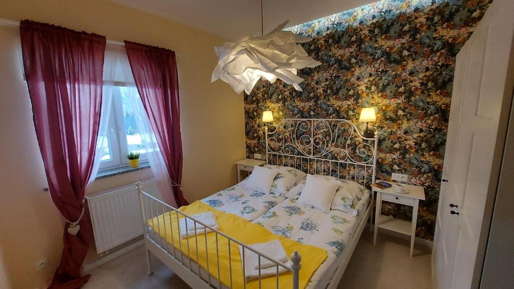 1 dormitorio con 1 cama con pared de flores en Apartamenty Malwa, en Lądek-Zdrój