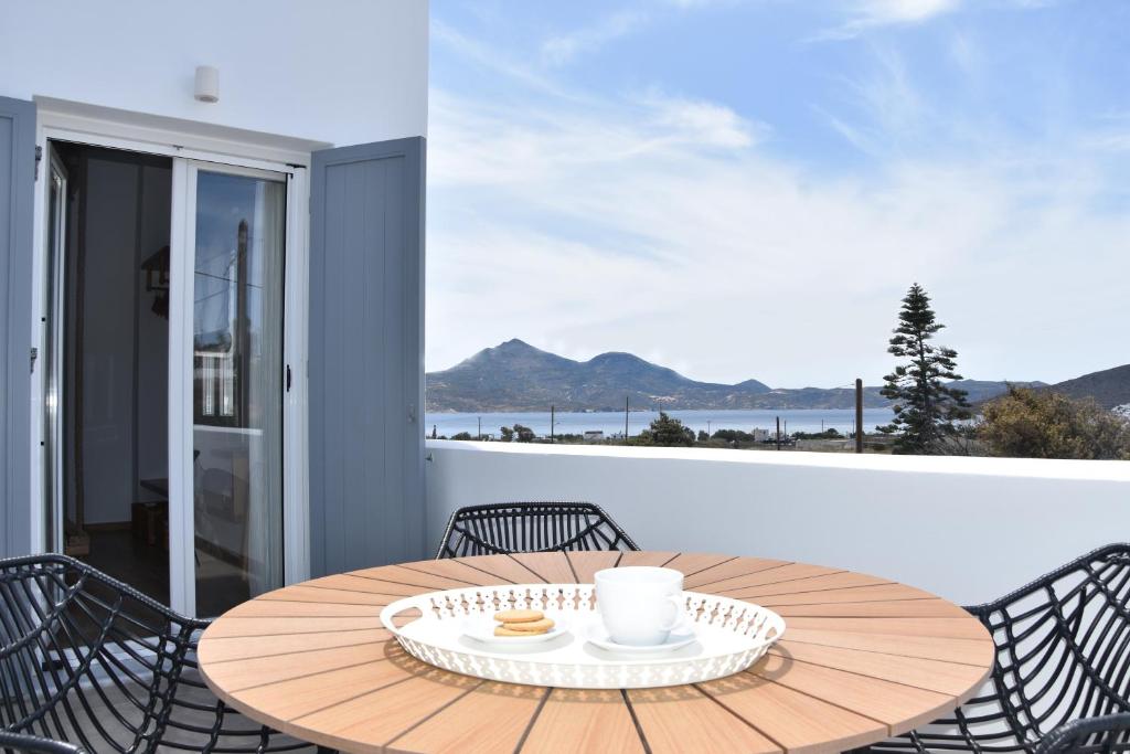 - une table en bois avec des chaises et une tasse de café sur le balcon dans l'établissement Villa Nelleas, à Adamas
