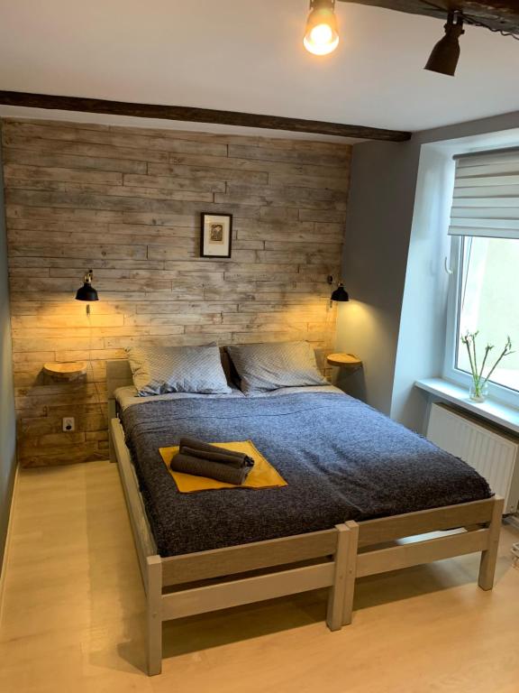 1 dormitorio con 1 cama grande y pared de madera en Apartament Salvador en Toruń