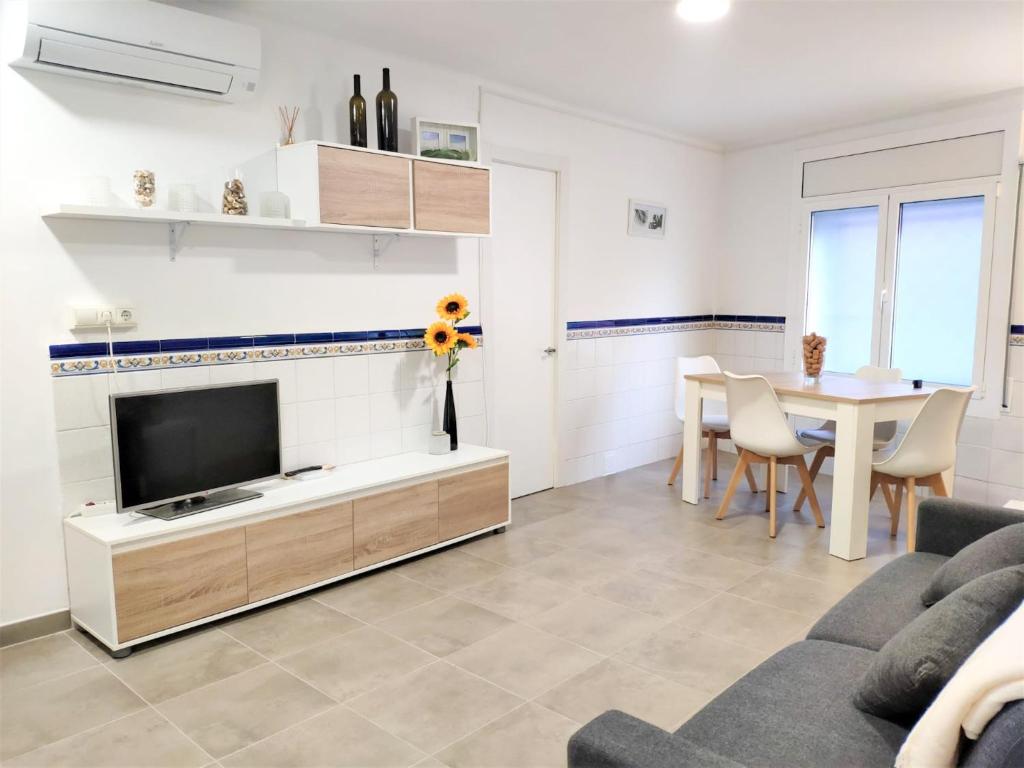 ein Wohnzimmer mit einem TV und einem Tisch in der Unterkunft Apartamento el Cau, acogedor y cerca del Montseny in Arbúcies