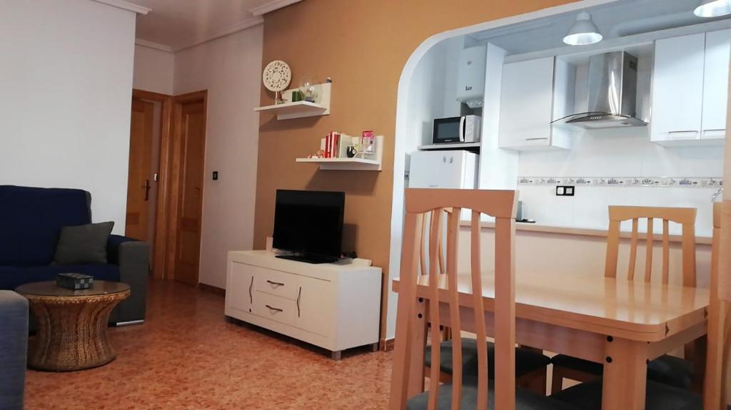 a kitchen and a living room with a table and a tv at Aitana Apartment in Gran Alacant