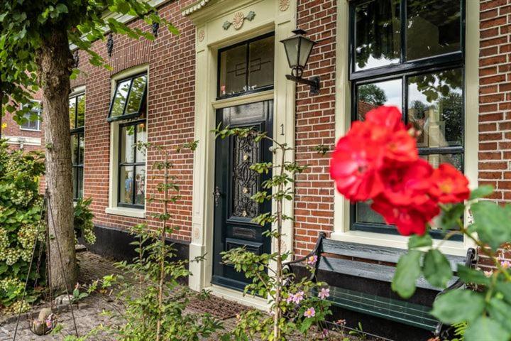 een rode bloem voor een bakstenen huis bij Bij de Friesche Poort in Bourtange