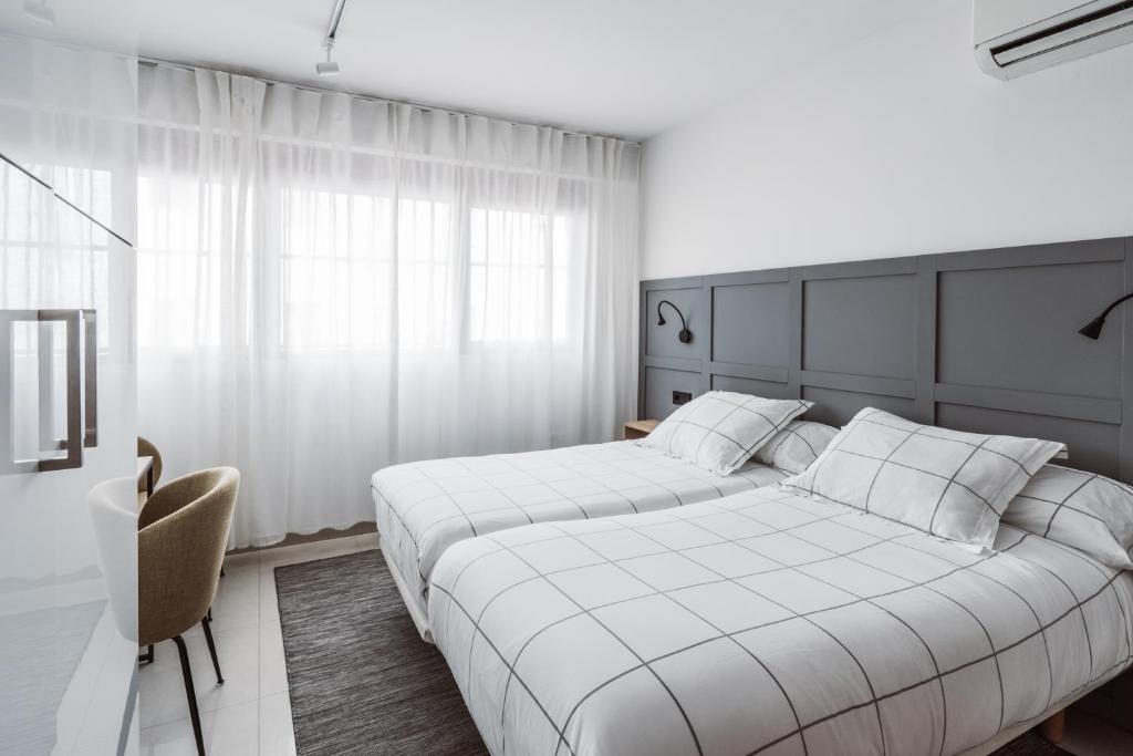Un dormitorio con 2 camas y una silla. en Chamberí Suites en Madrid