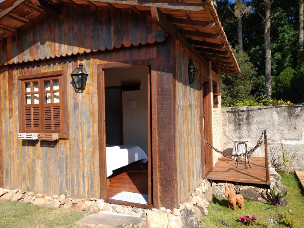 a small building with a porch and a bed in it at Chalé de madeira in Santa Cruz de Minas